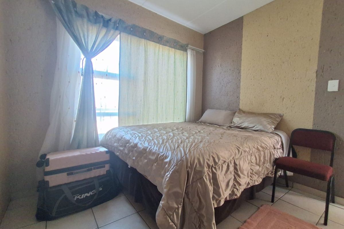 A bedroom featuring tiled flooring and a textured accent wall, providing a functional space with neutral tones.