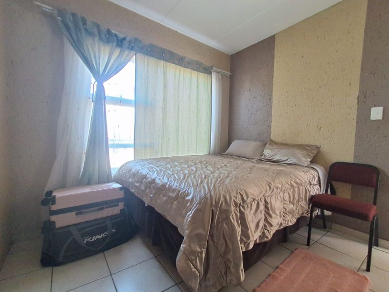 A bedroom featuring tiled flooring and a textured accent wall, providing a functional space with neutral tones.