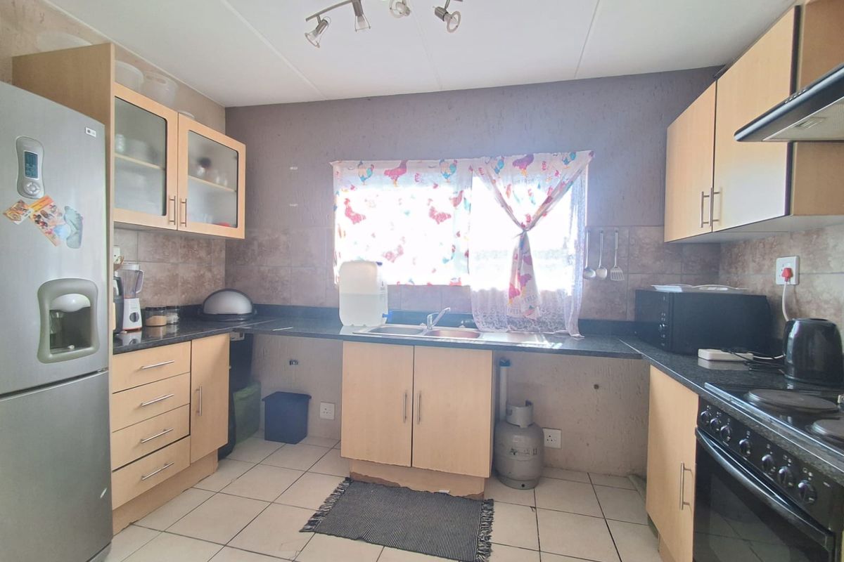 Functional kitchen featuring light wood cabinetry, granite countertops, tiled backsplash, and built-in stove with extractor fan.