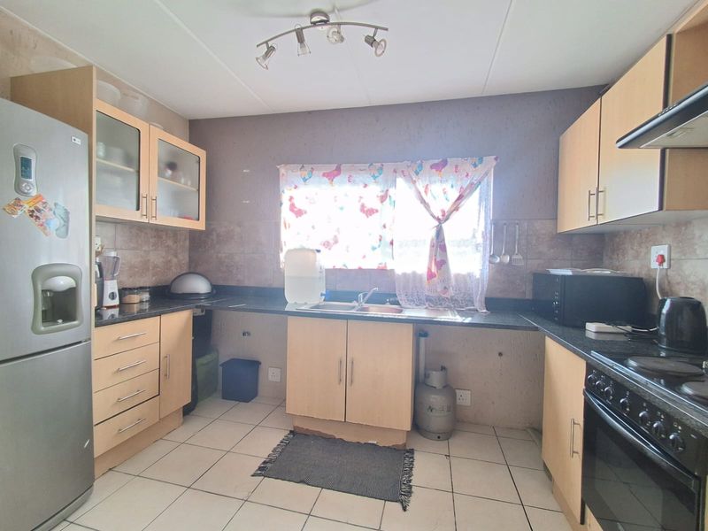 Functional kitchen featuring light wood cabinetry, granite countertops, tiled backsplash, and built-in stove with extractor fan.