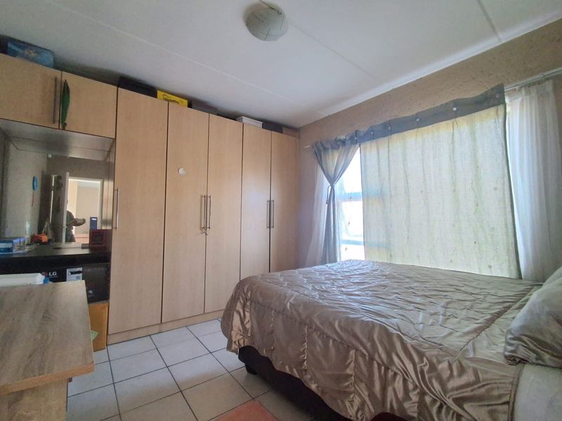 A bedroom featuring built-in cupboards and tiled flooring, offering functional storage space and a neutral layout.