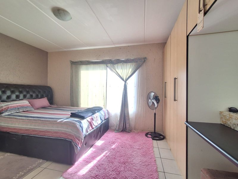 A bedroom featuring built-in cupboards, tiled flooring, and a sliding door providing natural light.