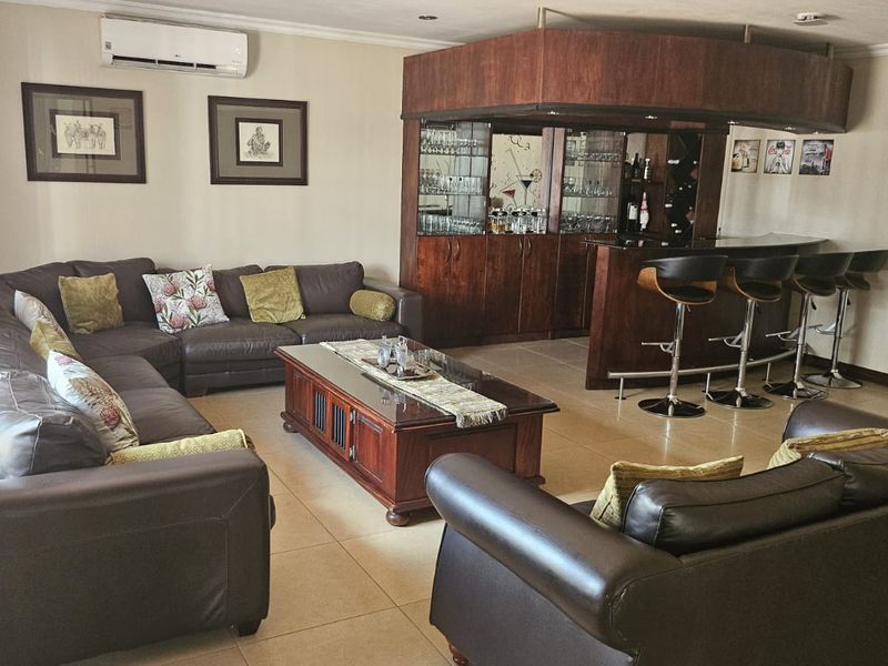 A spacious living area featuring a dedicated built-in bar with cabinetry and tiled flooring, complemented by a wall-mounted air conditioning unit.