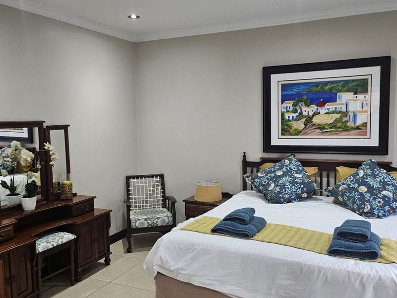 A well-maintained bedroom featuring neutral wall tones, tiled flooring, and recessed ceiling lighting, providing a comfortable and clean living space.