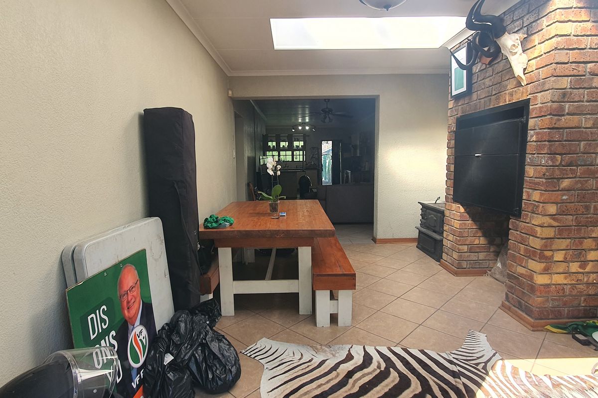 Living area featuring a prominent brick fireplace, tiled flooring, and a skylight, providing a functional space with potential for modernization.