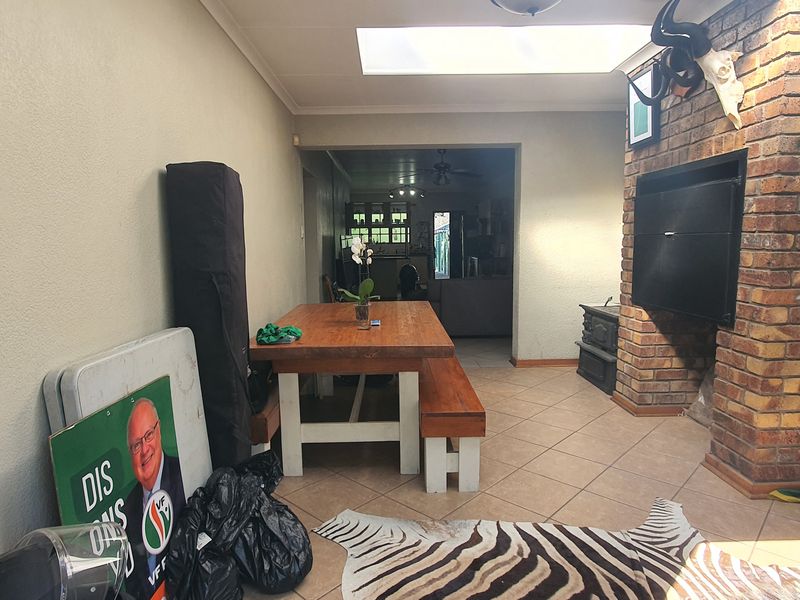 Living area featuring a prominent brick fireplace, tiled flooring, and a skylight, providing a functional space with potential for modernization.