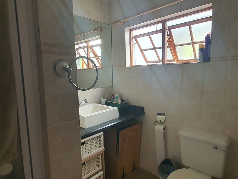 A functional bathroom featuring a vessel sink on a granite vanity, tiled walls, and a window providing natural light.