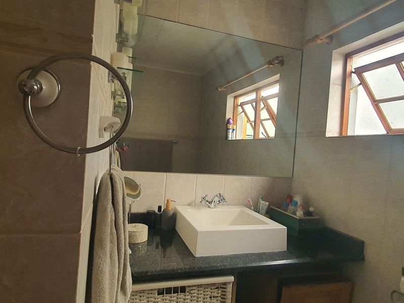 A functional bathroom featuring a modern vessel sink set on a granite vanity countertop with a large wall-mounted mirror and tiled finishes.