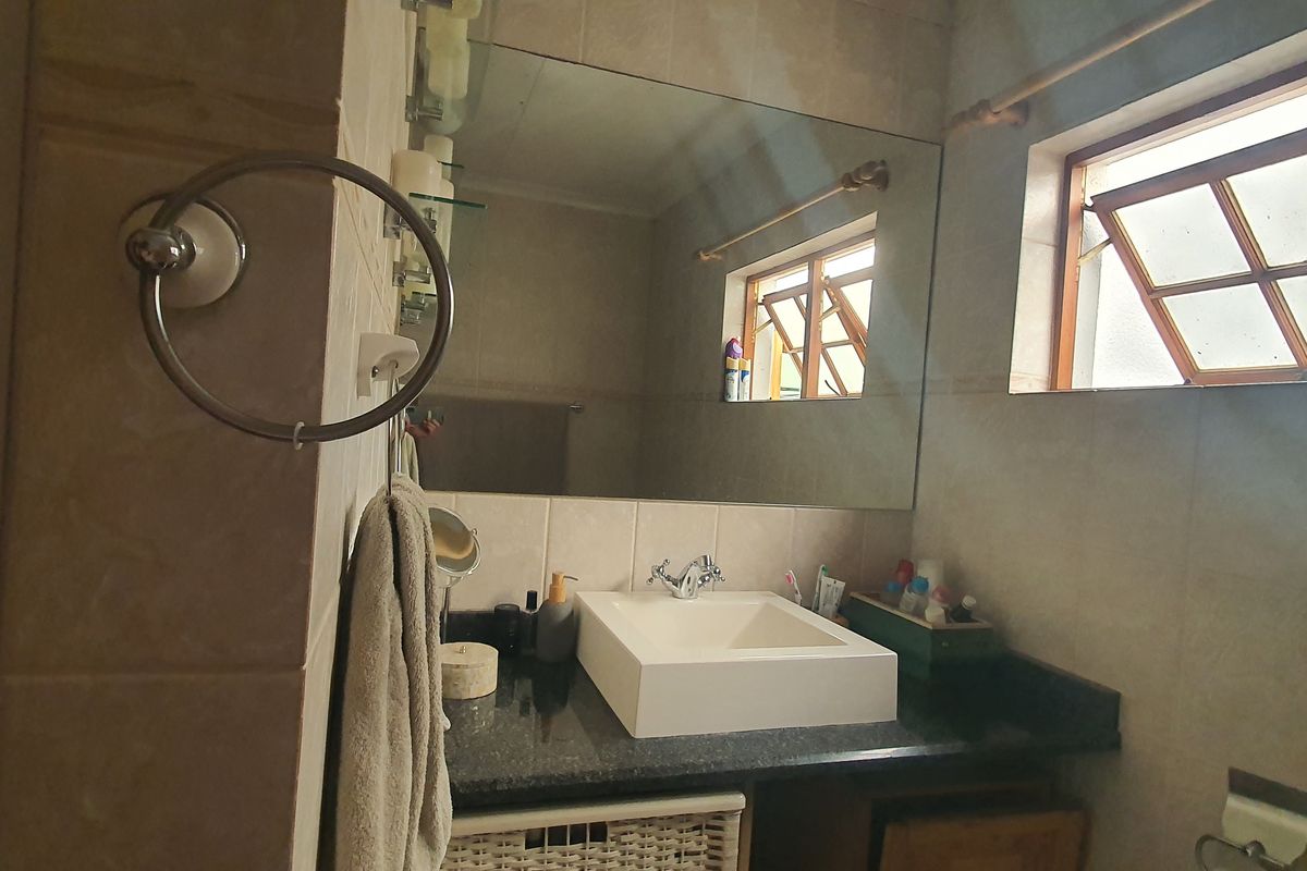 A functional bathroom featuring a modern vessel sink set on a granite vanity countertop with a large wall-mounted mirror and tiled finishes.