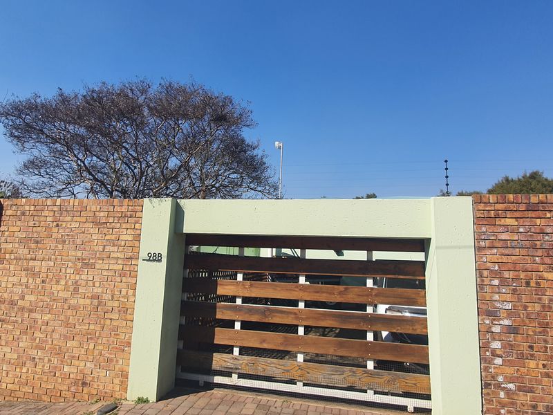 Front view of the property featuring a secure brick boundary wall, timber slat gate, and electric fencing.