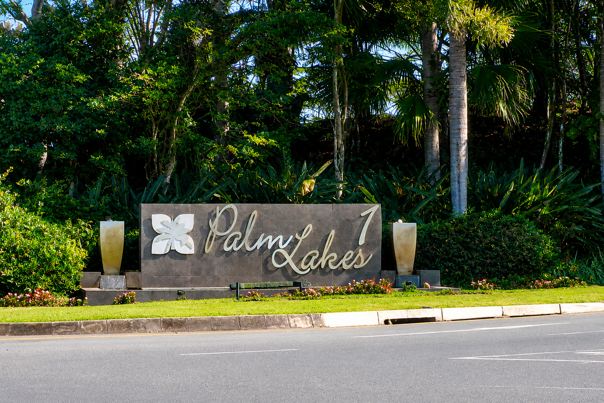 A well-maintained entrance sign for Palm Lakes estate, featuring professional landscaping and clear street-level visibility.