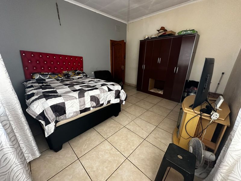 A bedroom featuring tiled flooring and a built-in wardrobe, requiring minor cosmetic updates to improve the overall finish and aesthetic appeal.