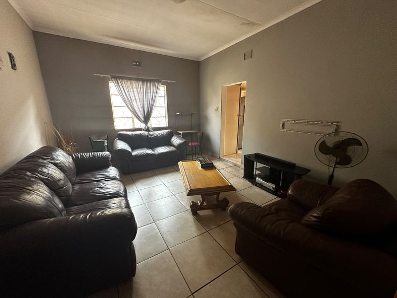 A living room featuring tiled flooring and coved ceilings, showing signs of wear including ceiling water staining and wall paint damage.