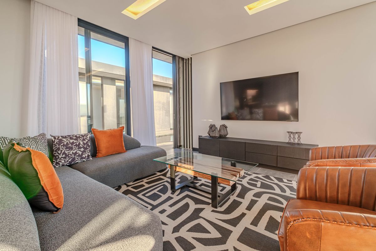 Modern living room featuring recessed ceiling lighting, large sliding glass doors providing natural light, and a sleek built-in media console.