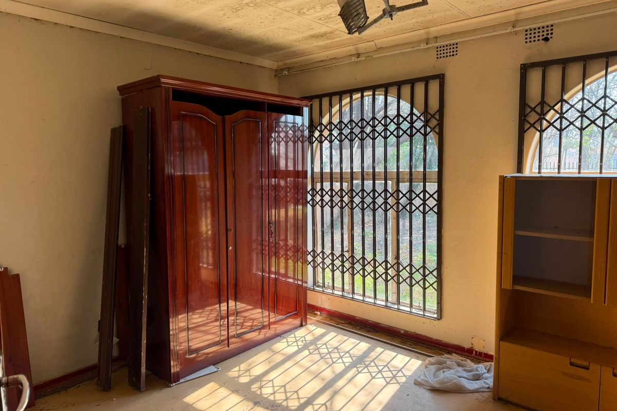 A bedroom featuring security gates on the windows, requiring significant renovation and cosmetic updates to restore the space.