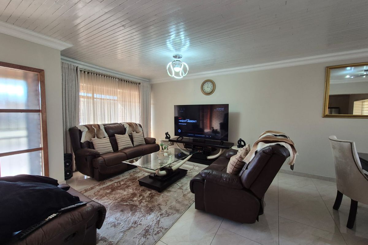 A well-maintained living room featuring tiled flooring, a distinctive tongue and groove ceiling, and large sliding glass doors providing natural light.