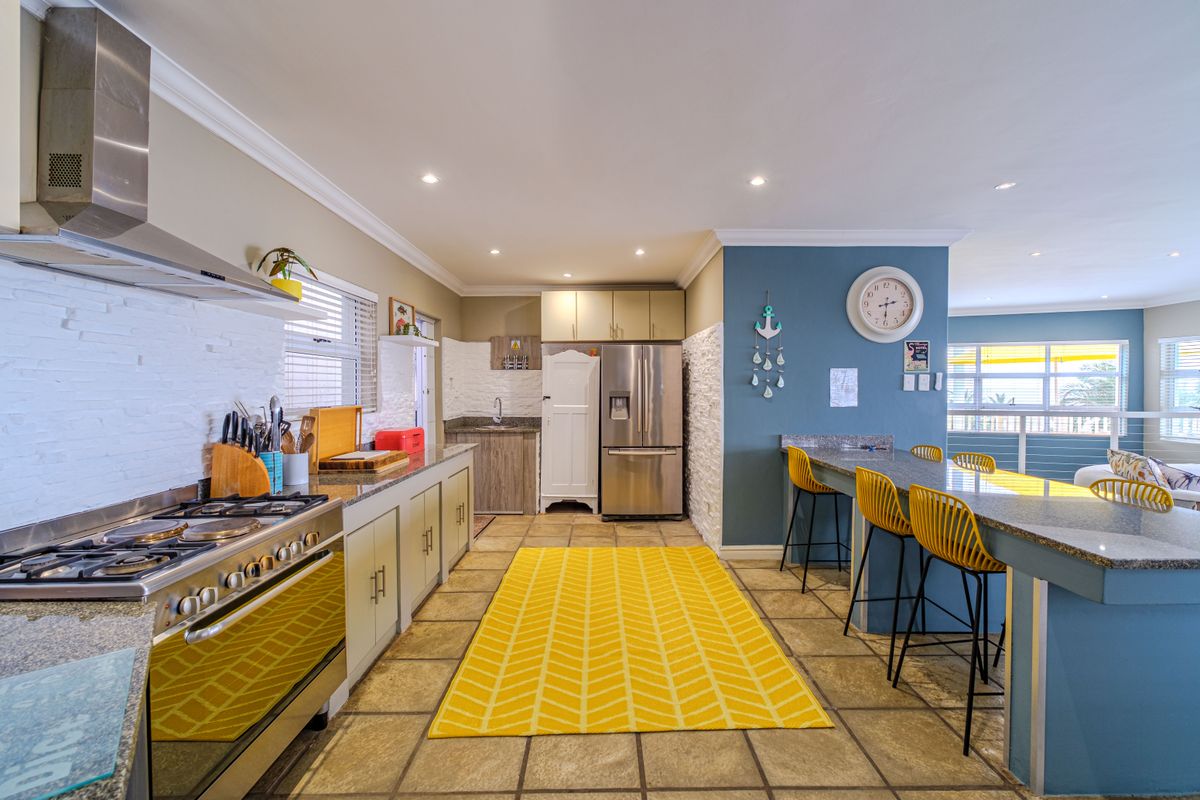 A well-appointed kitchen featuring granite countertops, stainless steel appliances, a stone veneer backsplash, and a functional breakfast bar area.