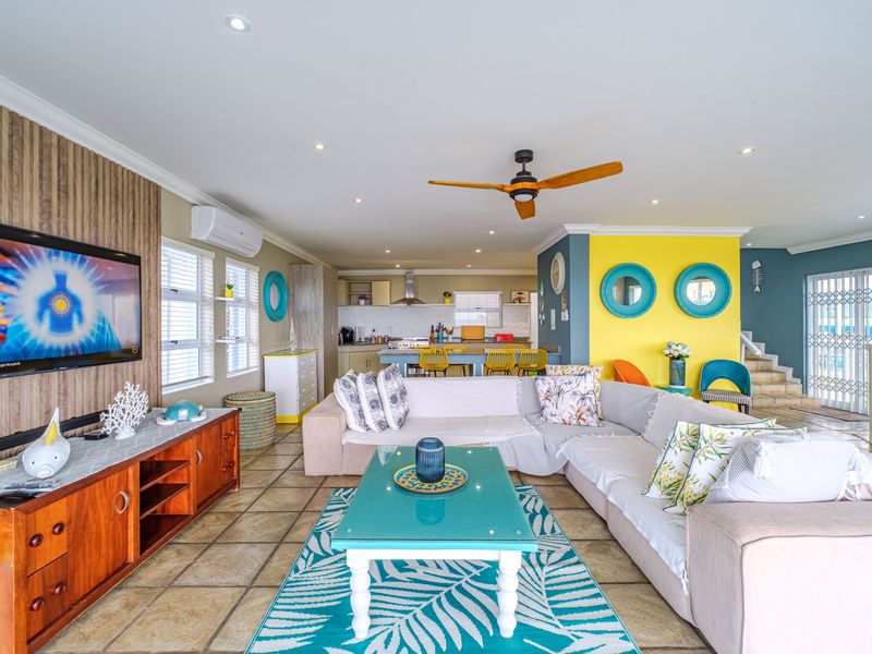 Spacious open-plan living and kitchen area featuring tiled floors, recessed lighting, a ceiling fan, and a modern kitchen layout with integrated cabinetry.