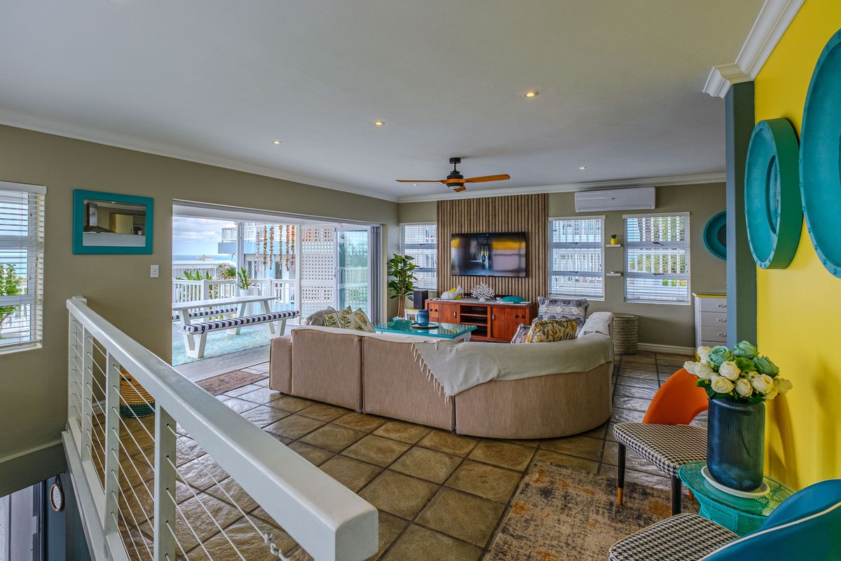 Spacious open-plan living area featuring tiled floors, a slatted timber feature wall, split-system air conditioning, and seamless access to an outdoor patio.