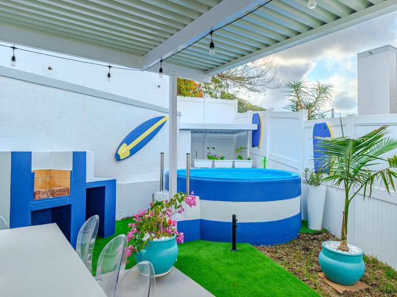 Outdoor entertainment area featuring a covered patio, built-in braai, and a circular plunge pool set within a private fenced garden.