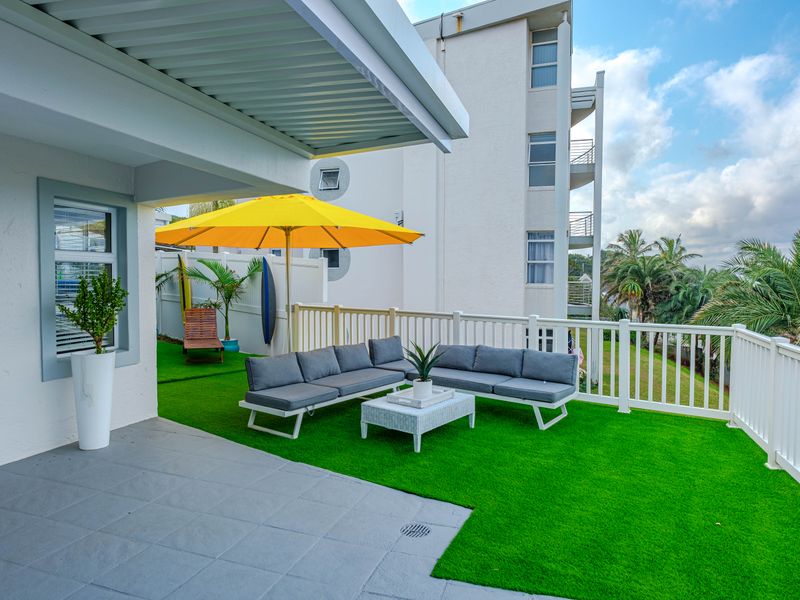 A well-maintained covered patio area featuring synthetic turf flooring and protective railings, providing a pleasant outdoor space for relaxation.