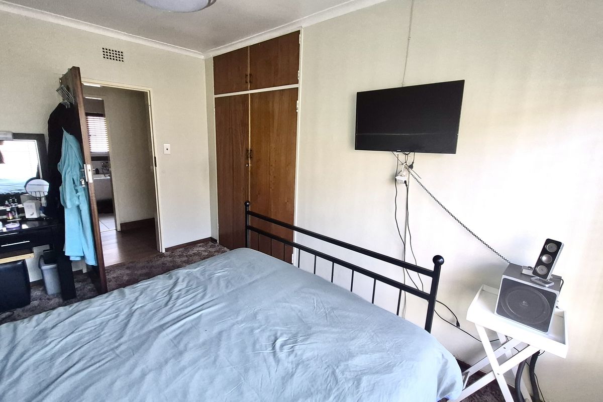 A functional bedroom featuring built-in wooden wardrobes and direct access to an adjoining room.