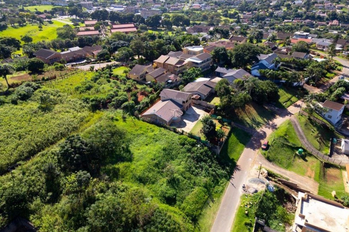 Aerial view of a vacant residential plot situated within an established suburban neighborhood, featuring surrounding greenery and access to local road infrastructure.