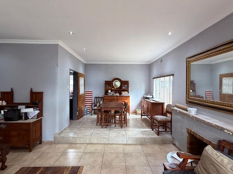 Open-plan living and dining area featuring tiled flooring, recessed lighting, and a fireplace with a raised dining platform.