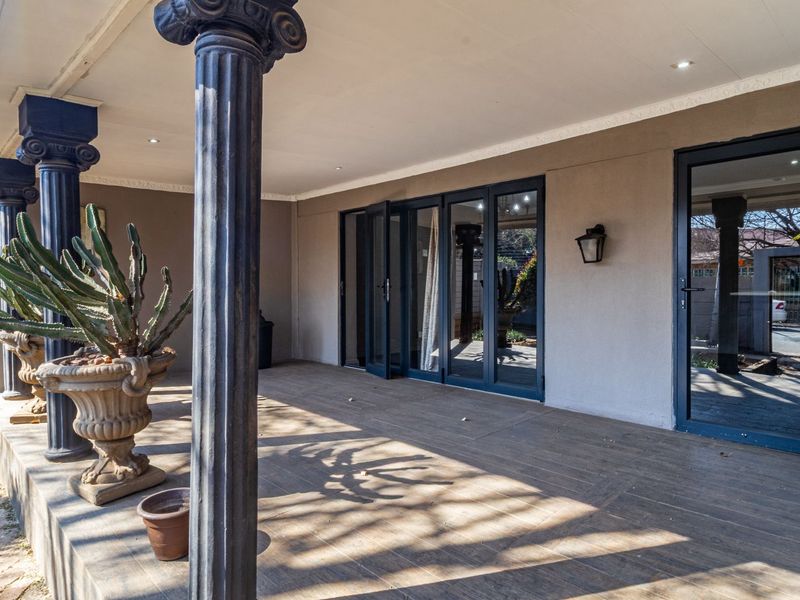 A spacious covered patio featuring decorative columns, tiled flooring, recessed lighting, and modern bi-fold doors providing seamless access to the interior living space.