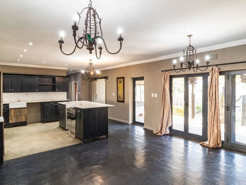 Spacious open-plan kitchen and living area featuring dark cabinetry, a central island, farmhouse sink, and direct access to the patio through french doors.