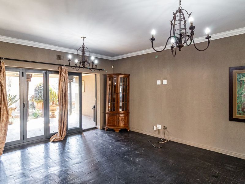 Spacious living room featuring dark tiled flooring, wrought iron chandeliers, and large aluminium stacker doors providing seamless access to the outdoor patio area.