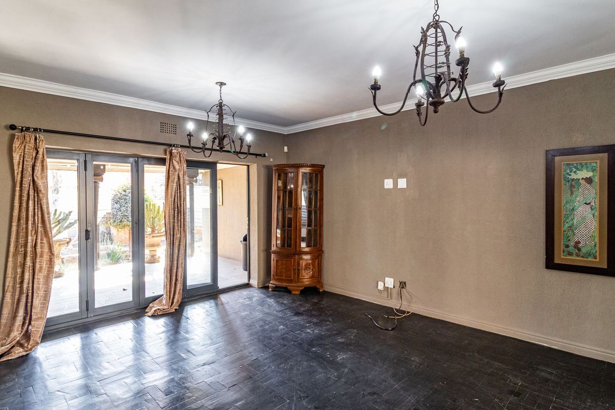 Spacious living room featuring dark tiled flooring, wrought iron chandeliers, and large aluminium stacker doors providing seamless access to the outdoor patio area.