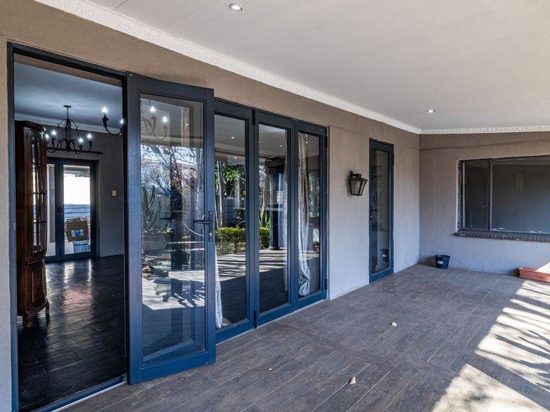 A spacious covered patio featuring modern bi-fold glass doors, tiled flooring, and recessed lighting, providing a seamless transition to the interior living space.