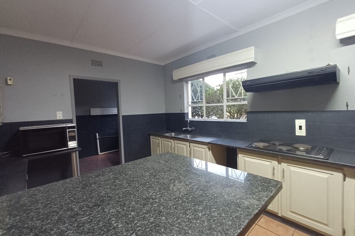 A functional kitchen featuring granite countertops, a built-in hob with extractor fan, and ample cabinetry, offering a solid foundation for modern updates.