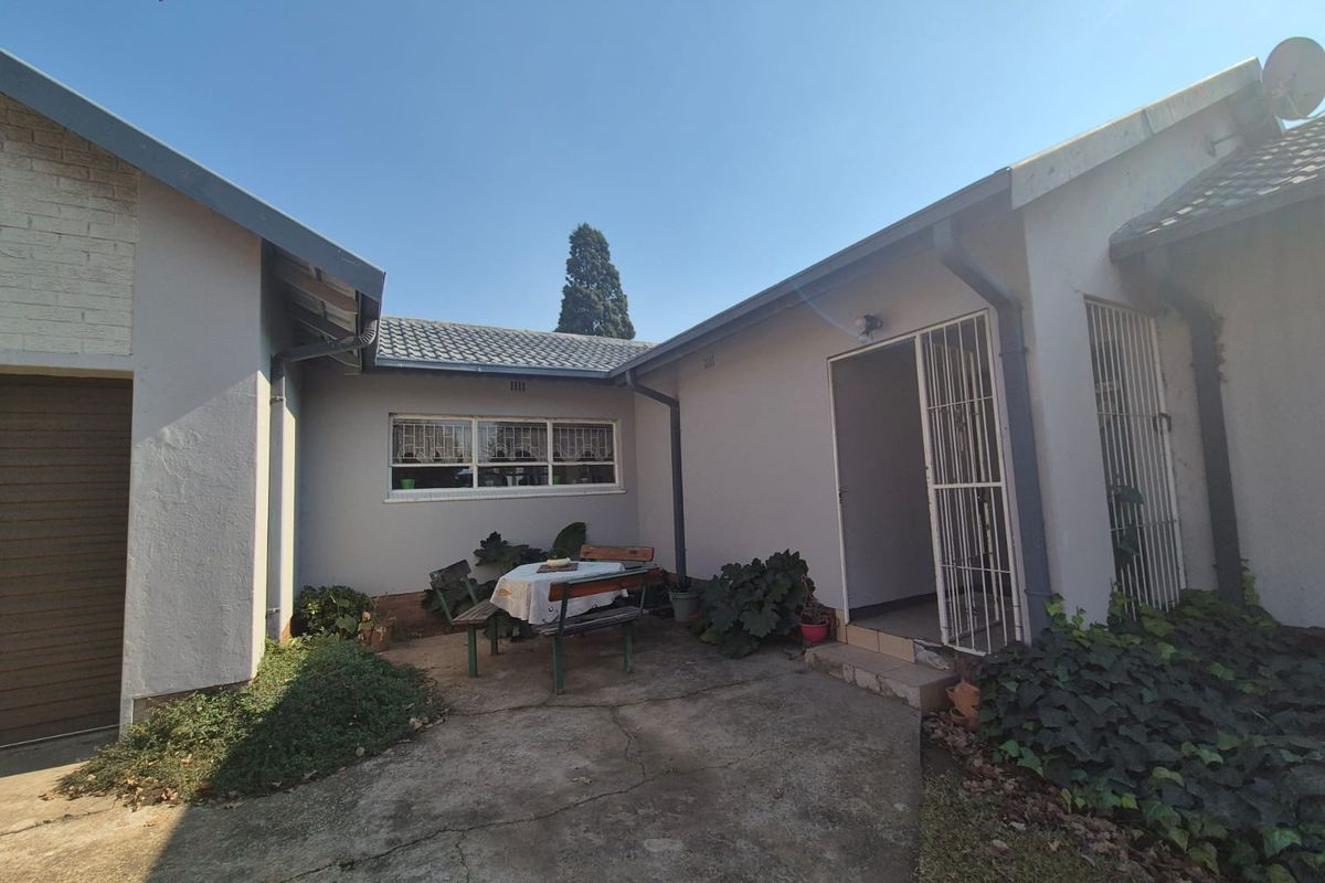 Rear courtyard area featuring concrete paving, security gates, and access to the main dwelling and garage, offering potential for outdoor living space enhancement.