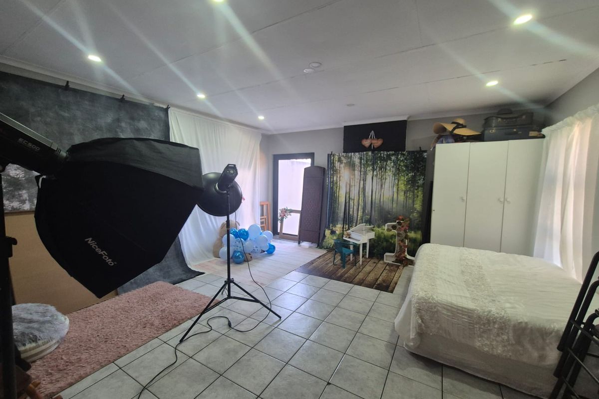 Spacious bedroom featuring tiled flooring, recessed downlighting, and a built-in wardrobe, currently utilized as a photography studio space.