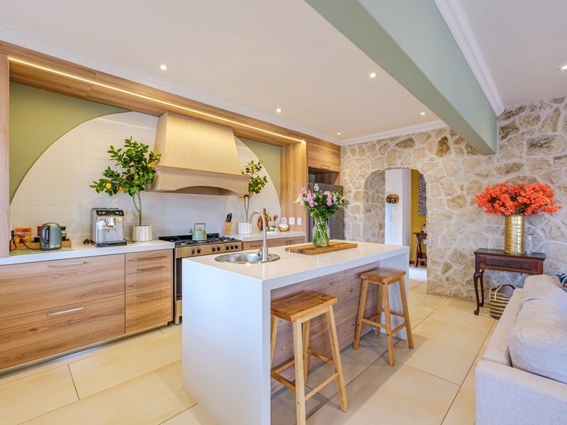 Modern open-plan kitchen featuring a central island, stone feature wall, and high-quality cabinetry, seamlessly integrated into the living space.
