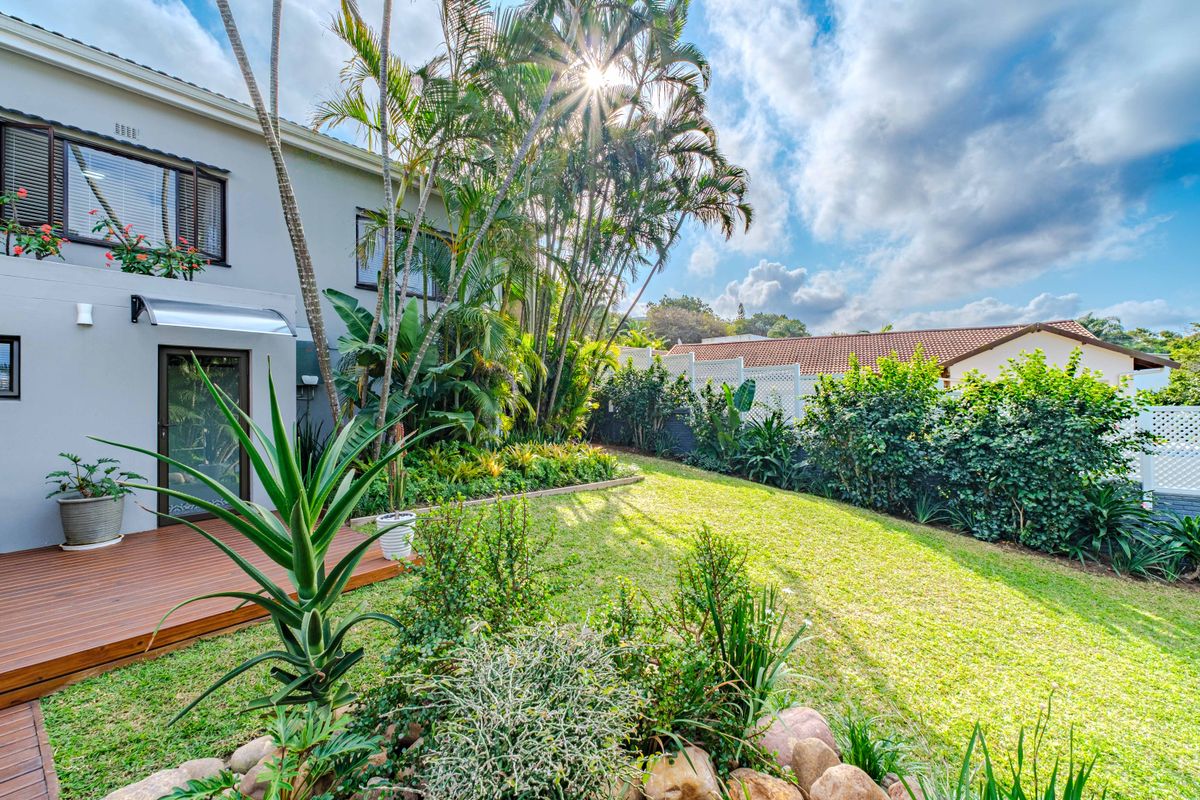A well-maintained rear garden featuring a timber deck, lush landscaping, and established greenery, providing a private outdoor space.