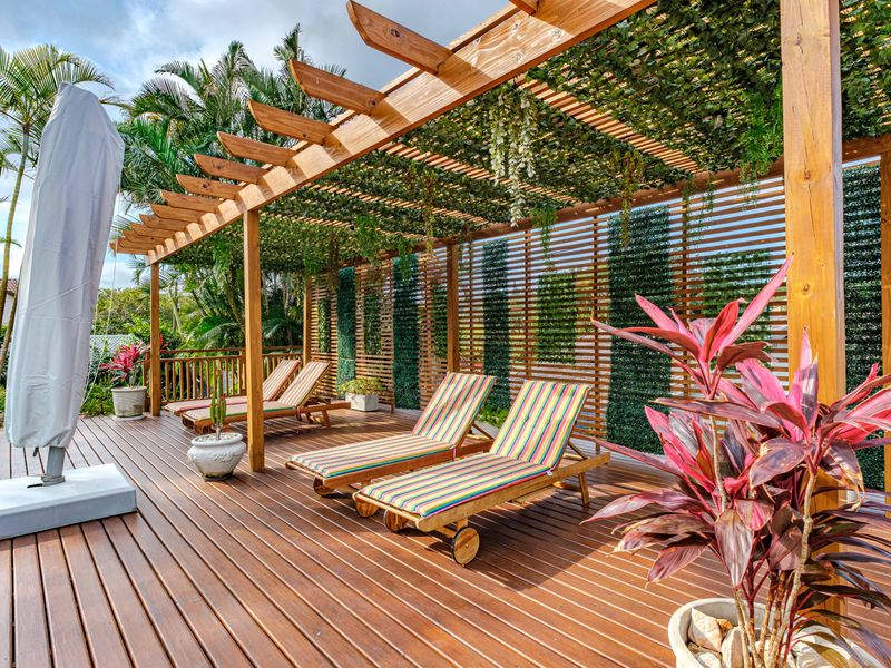 A well-maintained outdoor timber deck featuring a pergola with integrated vertical garden screening, providing a shaded and inviting entertainment area.