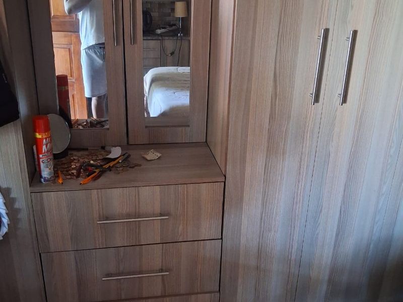 A bedroom featuring built-in wooden cabinetry with integrated wardrobe and vanity storage.