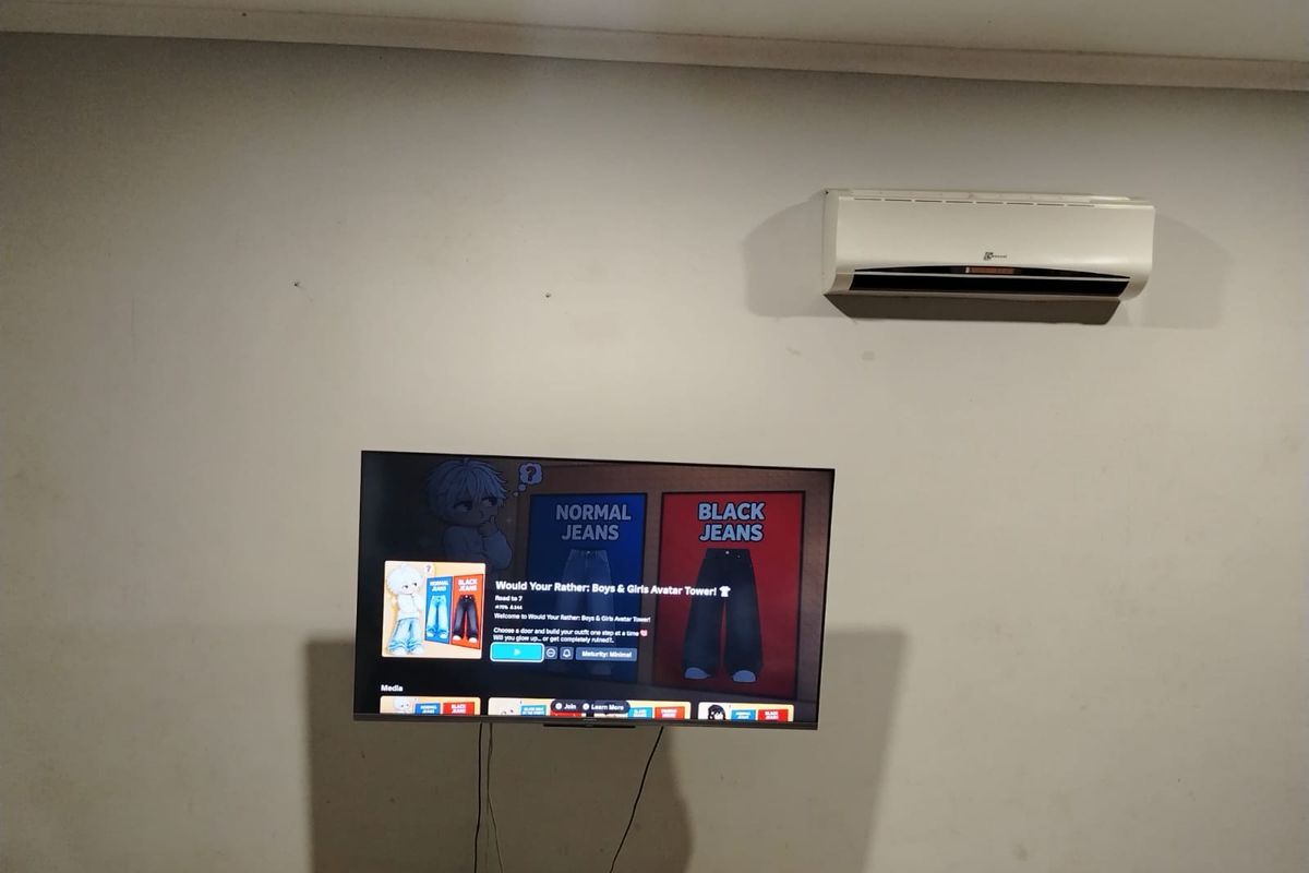 A living room wall featuring a mounted air conditioning unit and a television screen.