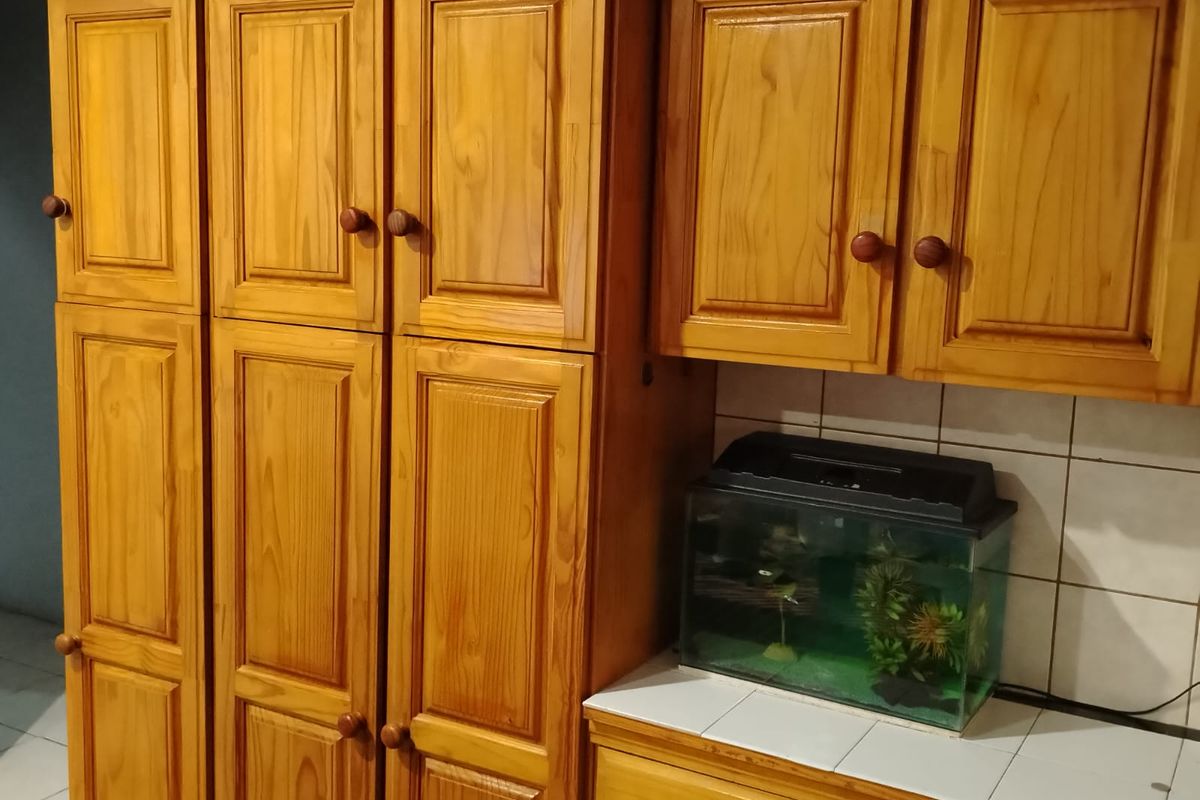 A kitchen area featuring traditional built-in wooden cabinetry, a tiled backsplash, and a tiled countertop surface.