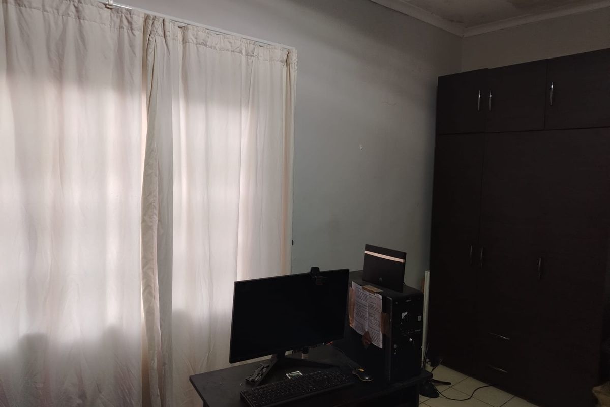 A bedroom featuring a dark built-in wardrobe, tiled flooring, and visible water staining on the ceiling.