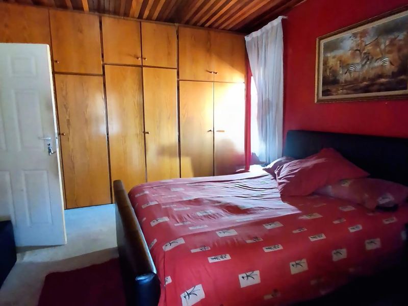 A bedroom featuring built-in wooden cabinetry and a traditional wooden tongue and groove ceiling with an integrated ceiling fan.