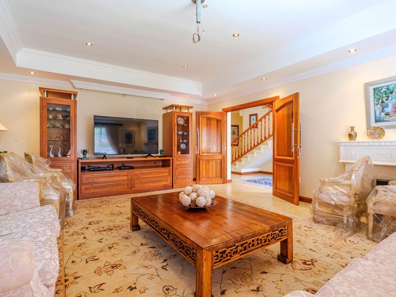 Spacious living room featuring built-in wooden cabinetry, a fireplace mantel, crown molding, and recessed lighting, with an open transition to the staircase area.