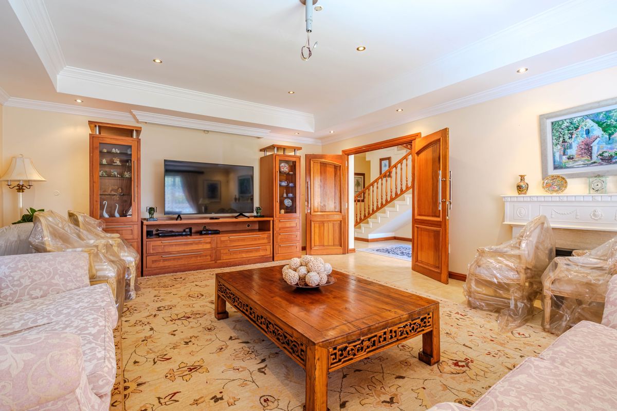 Spacious living room featuring built-in wooden cabinetry, a fireplace mantel, crown molding, and recessed lighting, with an open transition to the staircase area.