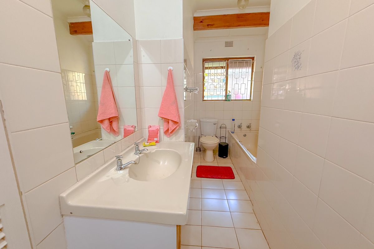A functional bathroom featuring a vanity basin, bathtub, toilet, and tiled finishes, offering a clean layout with potential for modern updates.