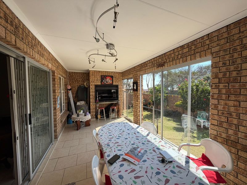 Enclosed patio featuring a built-in braai, tiled flooring, and large sliding glass doors providing direct access to the garden.