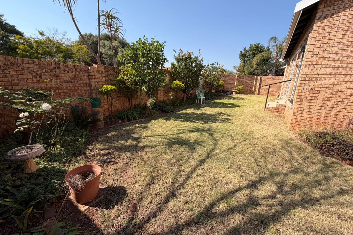 A private rear garden featuring a well-maintained lawn, established trees, and secure brick boundary walls, providing a peaceful outdoor space.