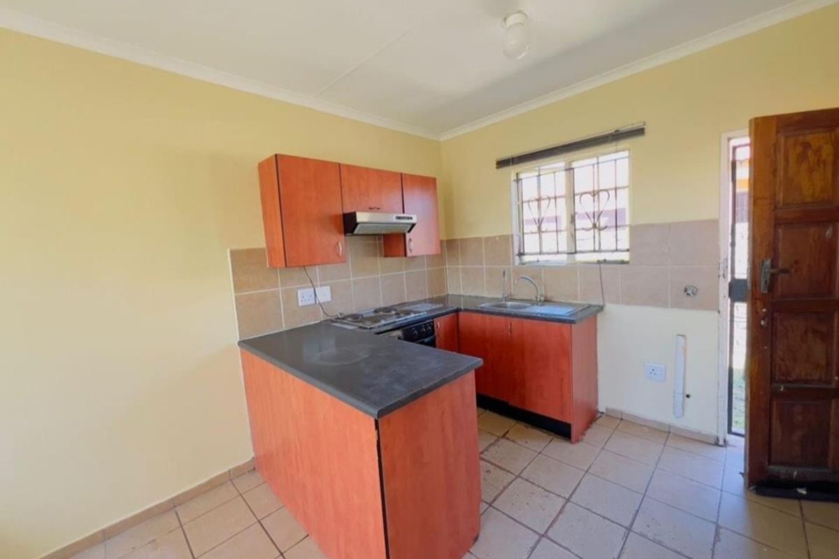 A functional kitchen featuring built-in cabinetry, laminate countertops, a stainless steel sink, and tiled flooring, offering a clean and practical workspace.